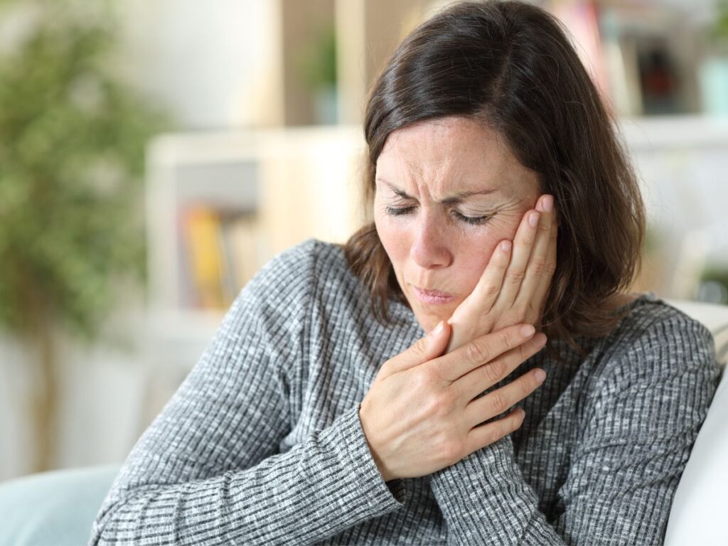 woman holding jaw in discomfort
